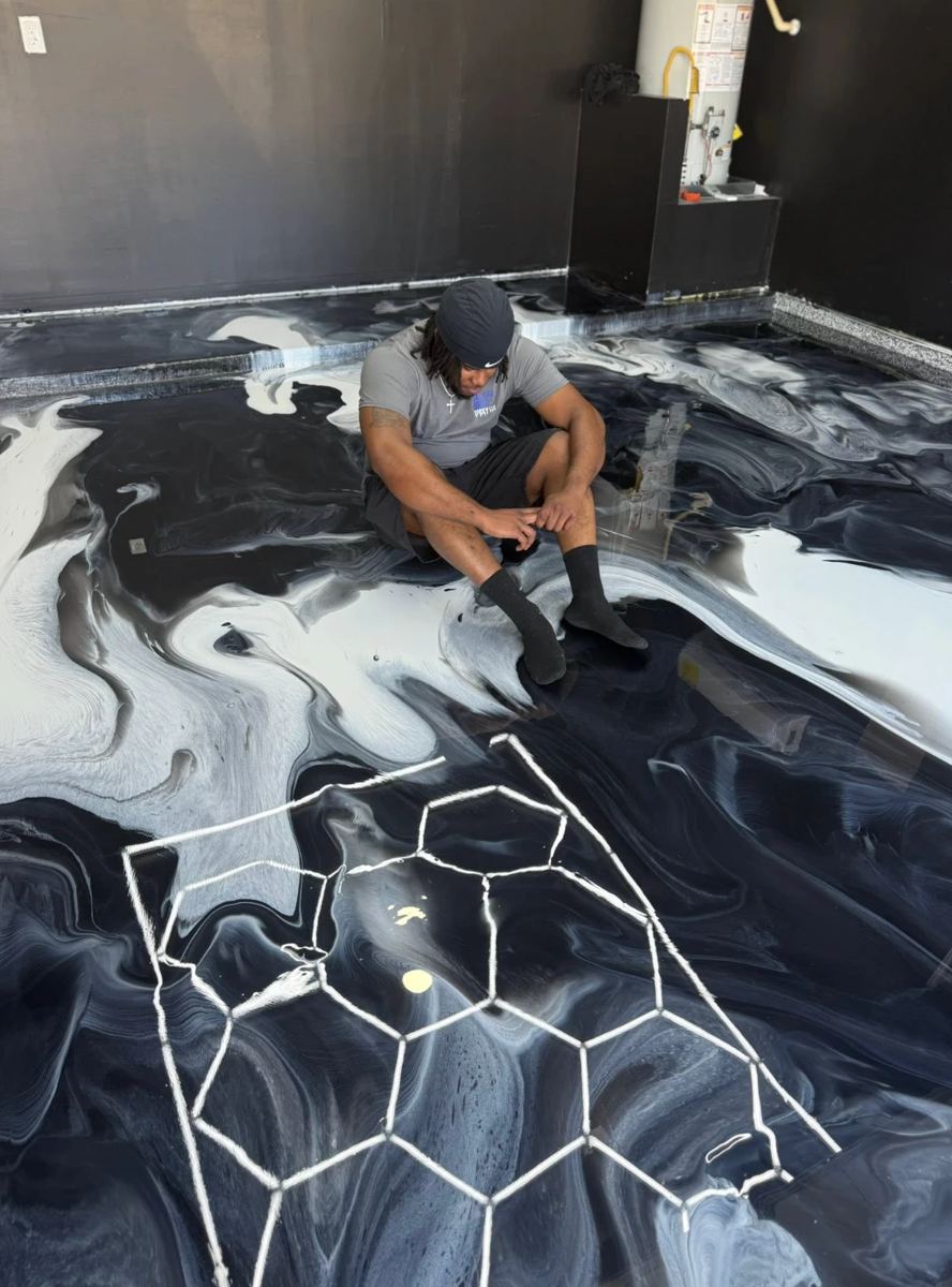 Cody Green checking a black and white metallic epoxy floor with a glowing hexagon design