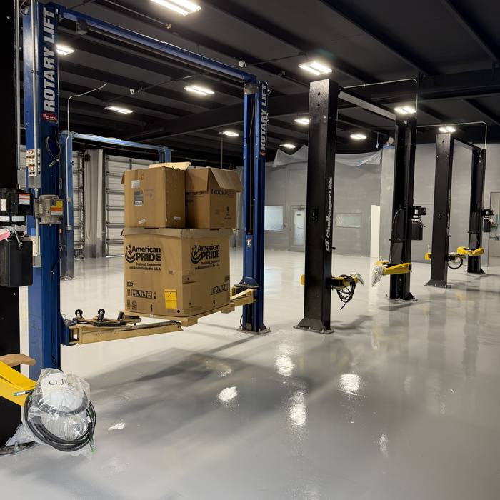 Dark auto shop with lifts and a glossy coated floor