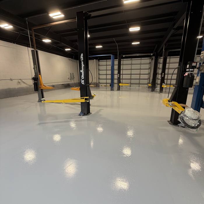 Auto shop with vehicle lifts over a glossy dark floor