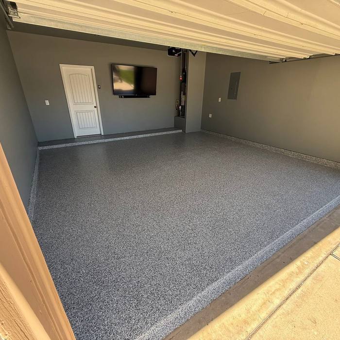 Finished gray flake epoxy garage floor with a wall mounted TV