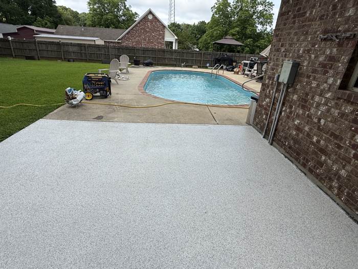 Coated pool deck wrapping a backyard swimming pool