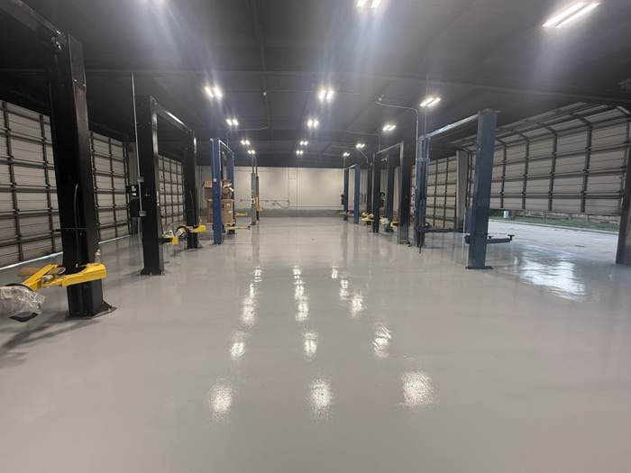 Fresh solid color epoxy floor in a commercial shop with vehicle lifts